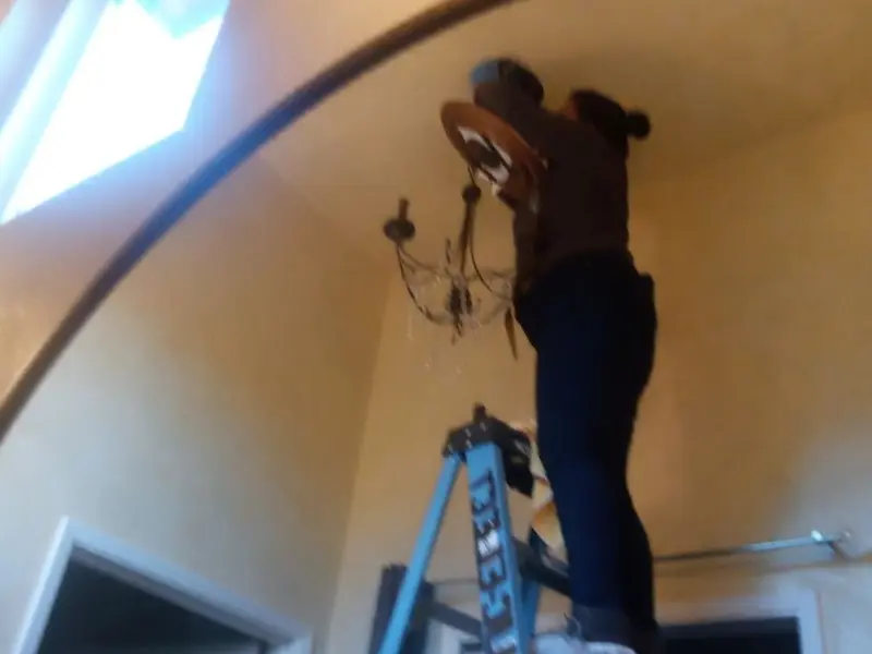 Electrician installing a chandelier in a Berkley residence